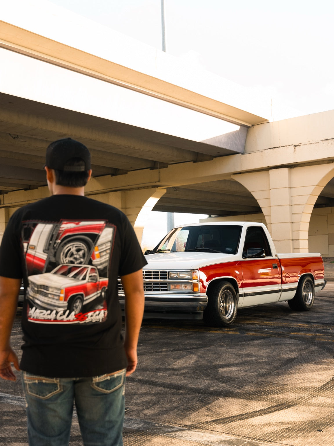 Model wearing Marca Classica OBS shirt beside red and white Chevy truck